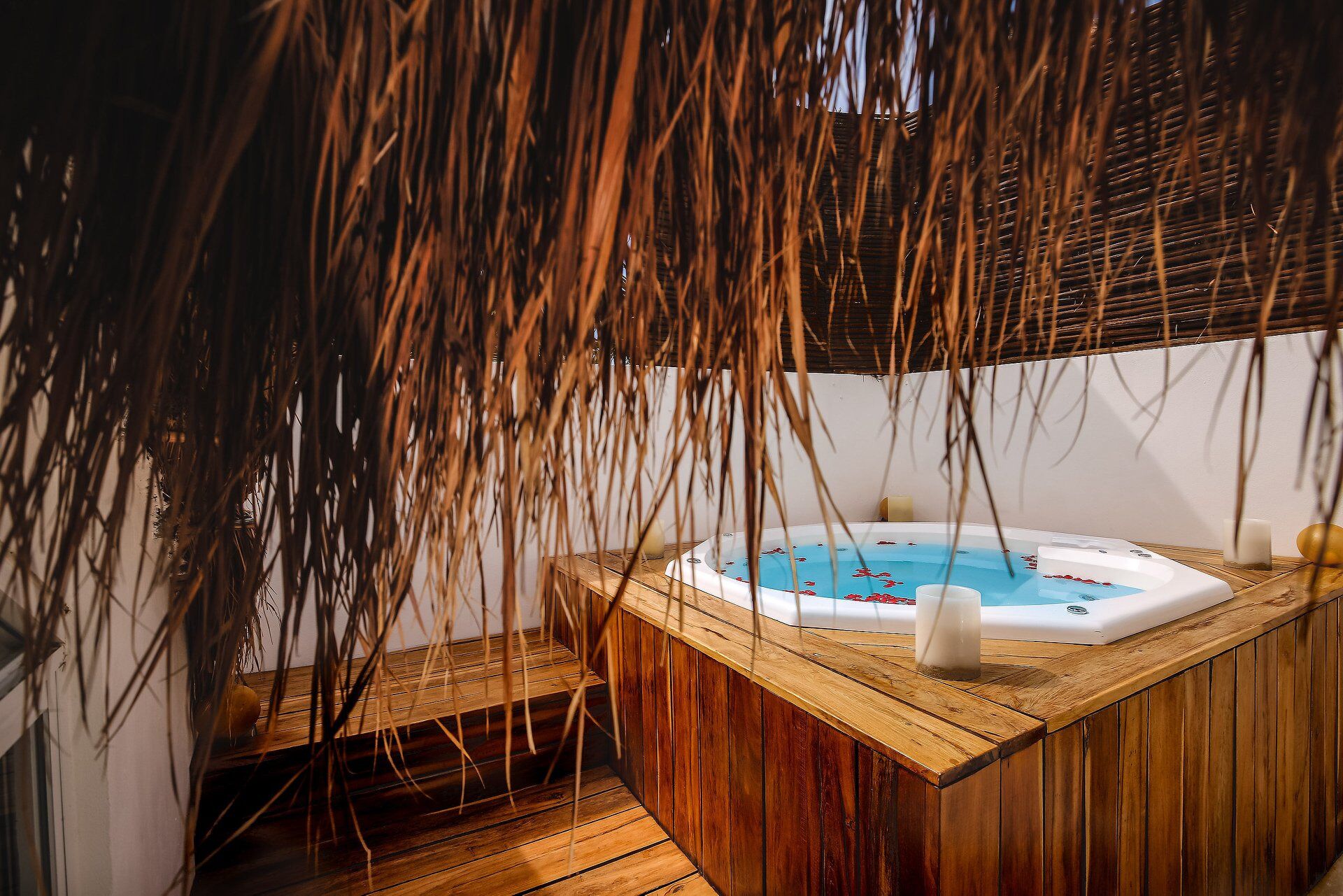 A wooden hot tub with a blue interior, surrounded by bamboo decor.