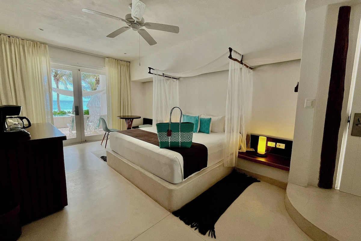 A modern bedroom with a bed, a desk, and a ceiling fan.