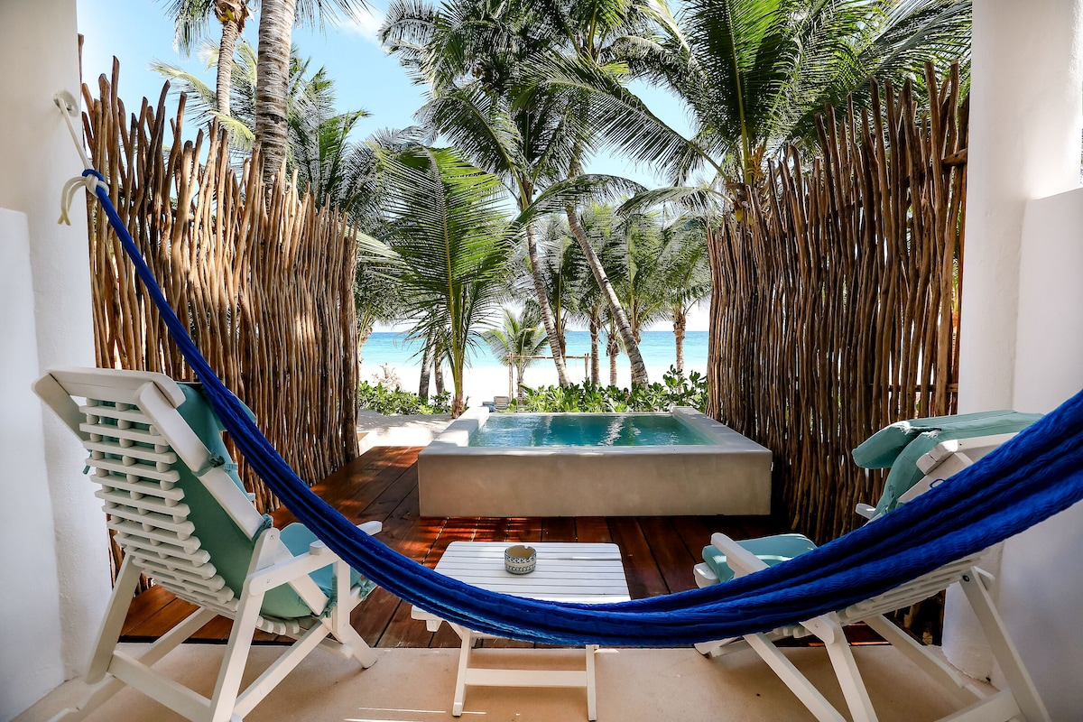 patio of Cabanas Tulum, with lounge chairs, swing, and plunge pool fronting the beach