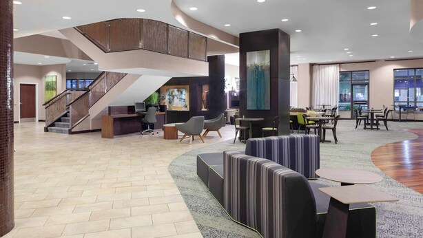 A spacious lobby with a curved carpet, seating areas, a staircase, and a reception desk. - Courtyard by Marriott Downtown Memphis (Memphis)