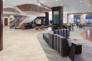 Relax in the stylish lobby, featuring a central seating area, staircase, and reception desk.