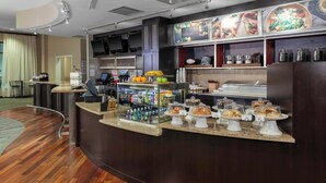 A hotel reception area with a curved counter, a coffee machine, and a display of pastries and snacks. - Courtyard by Marriott Downtown Memphis (Memphis)