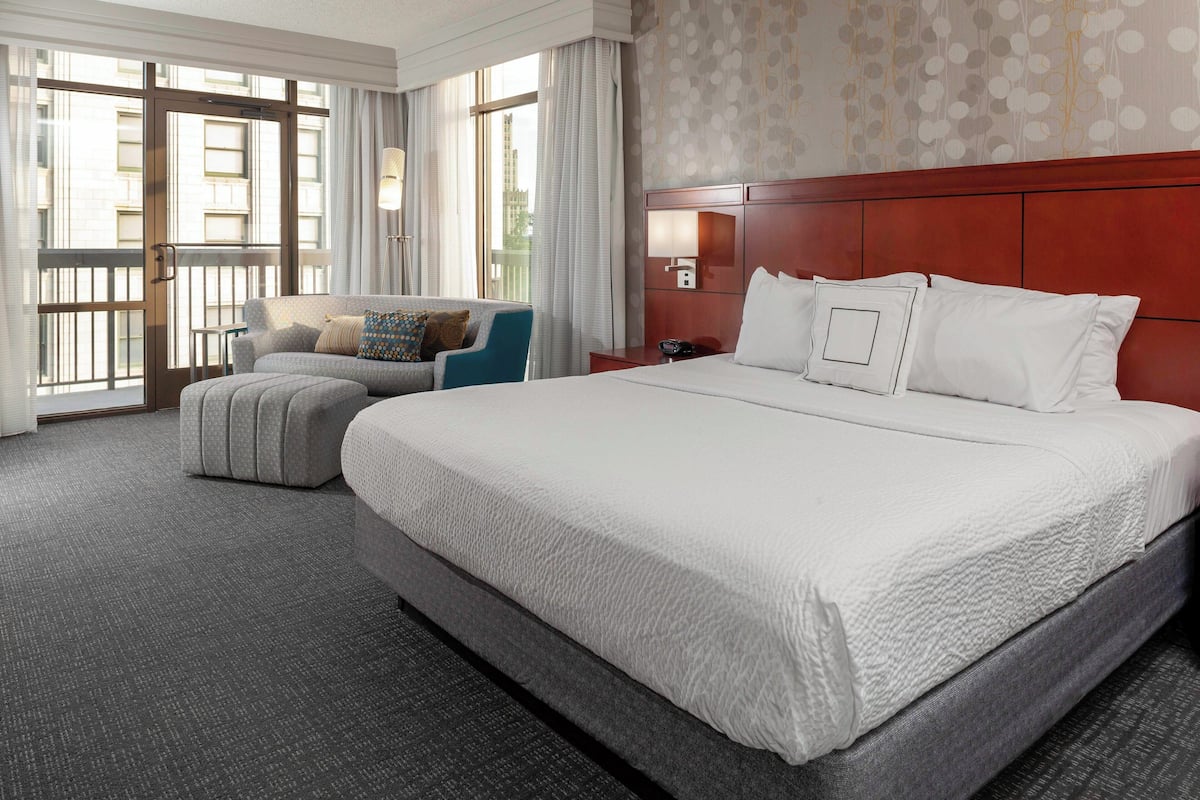 A hotel room with a large bed, a sofa, a chair, and a desk.