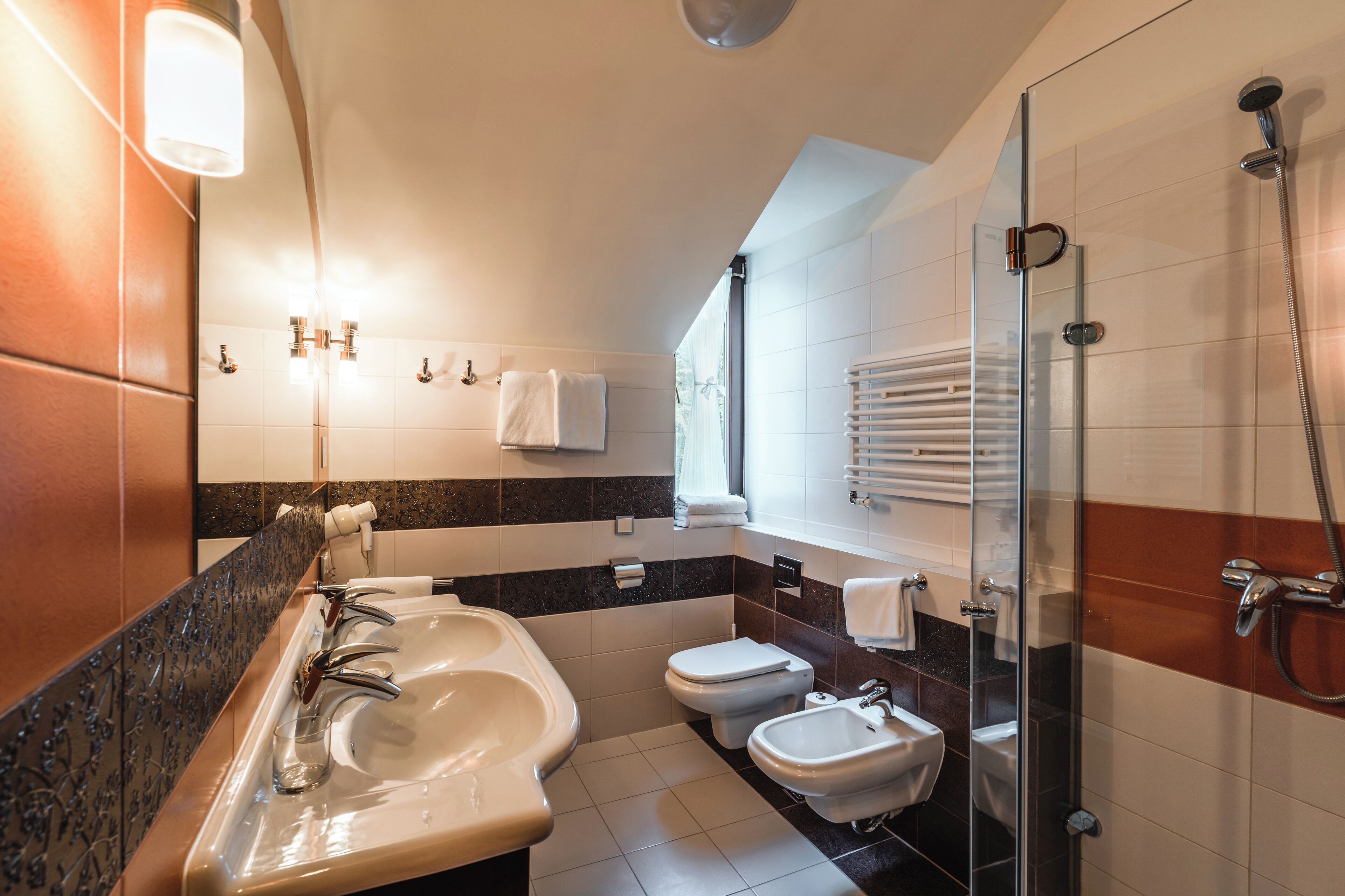 A modern bathroom with a glass-enclosed shower, a double sink vanity, and a toilet.