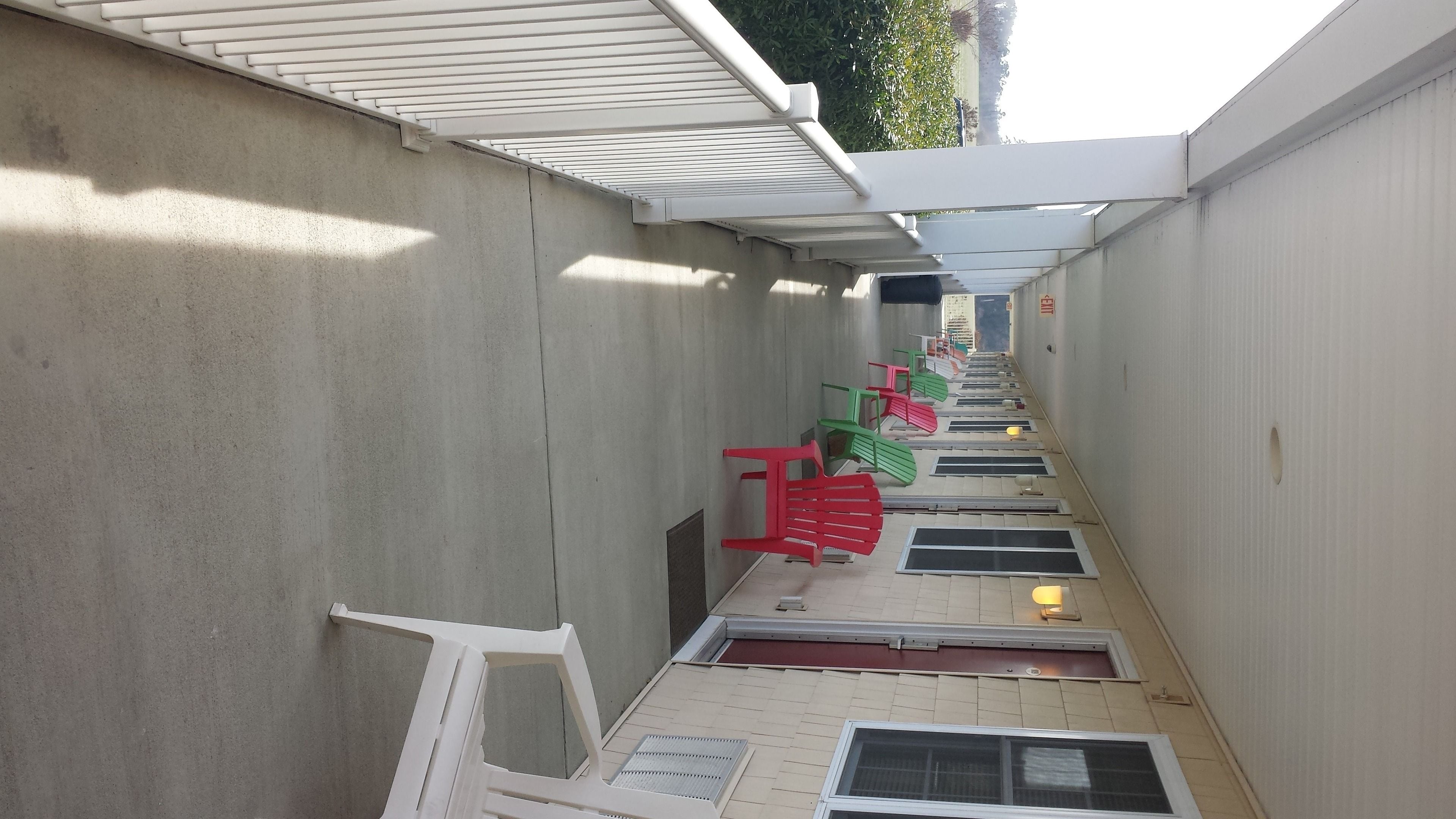 A narrow corridor with concrete walls, a sloped ceiling, and a series of windows along the length.