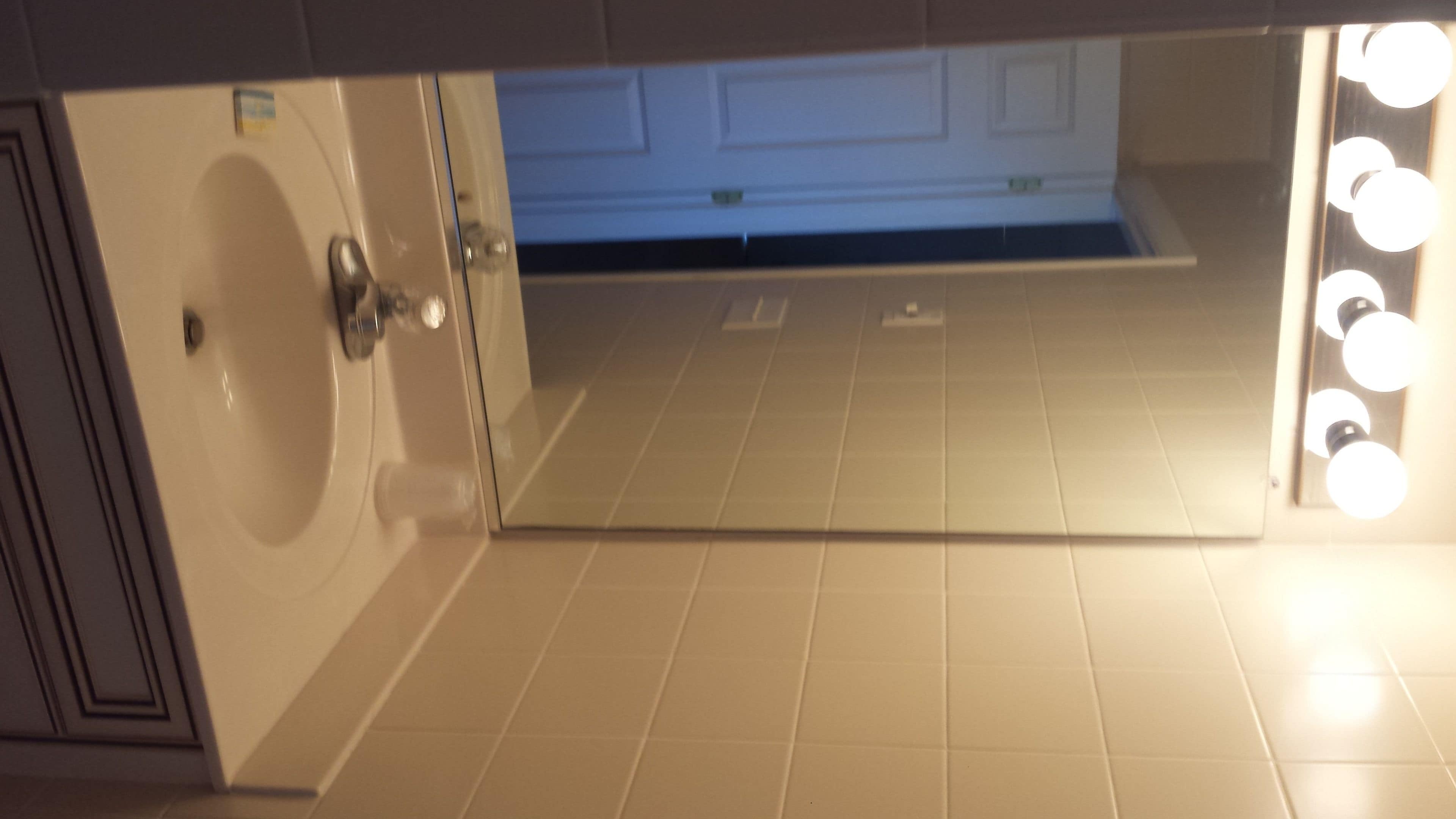 A bathroom with a sink, mirror, and lights.