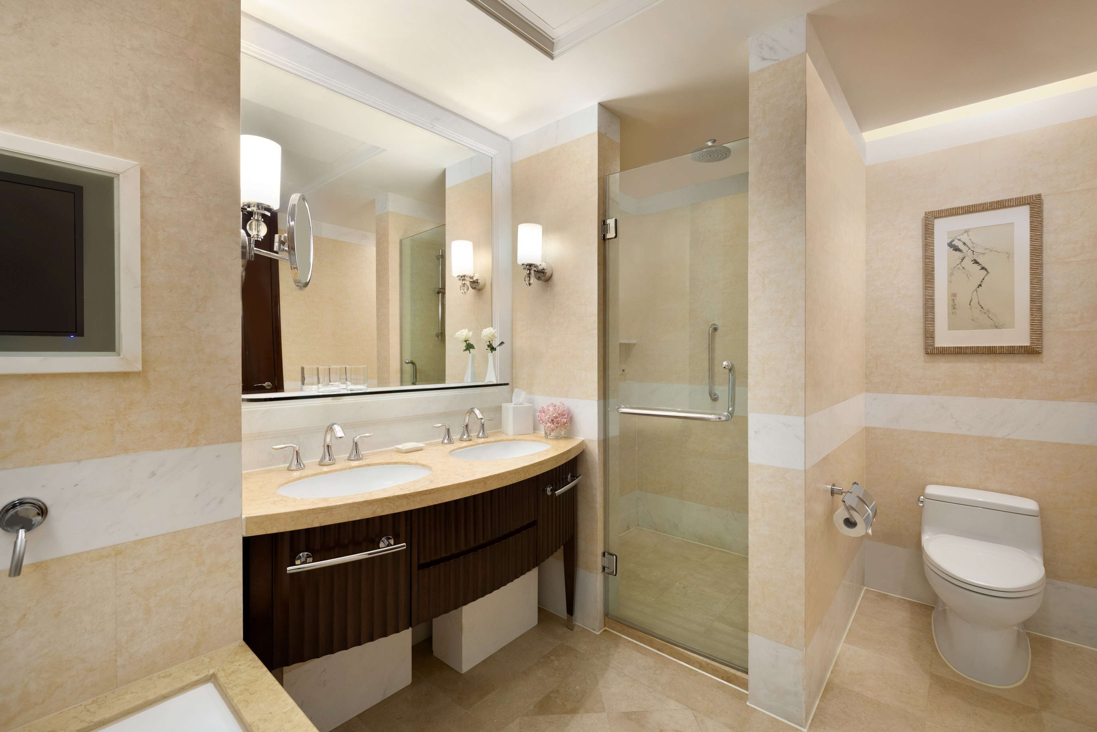 A modern bathroom with a double sink vanity, a glass-enclosed shower, and a toilet.