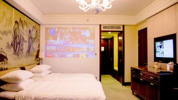 Una habitación de hotel con una cama grande, televisión, cómoda y una pantalla de proyección mostrando un evento deportivo.
