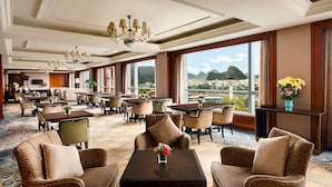 A spacious hotel lobby with multiple seating areas, a chandelier, and large windows offering a view of the city and mountains.