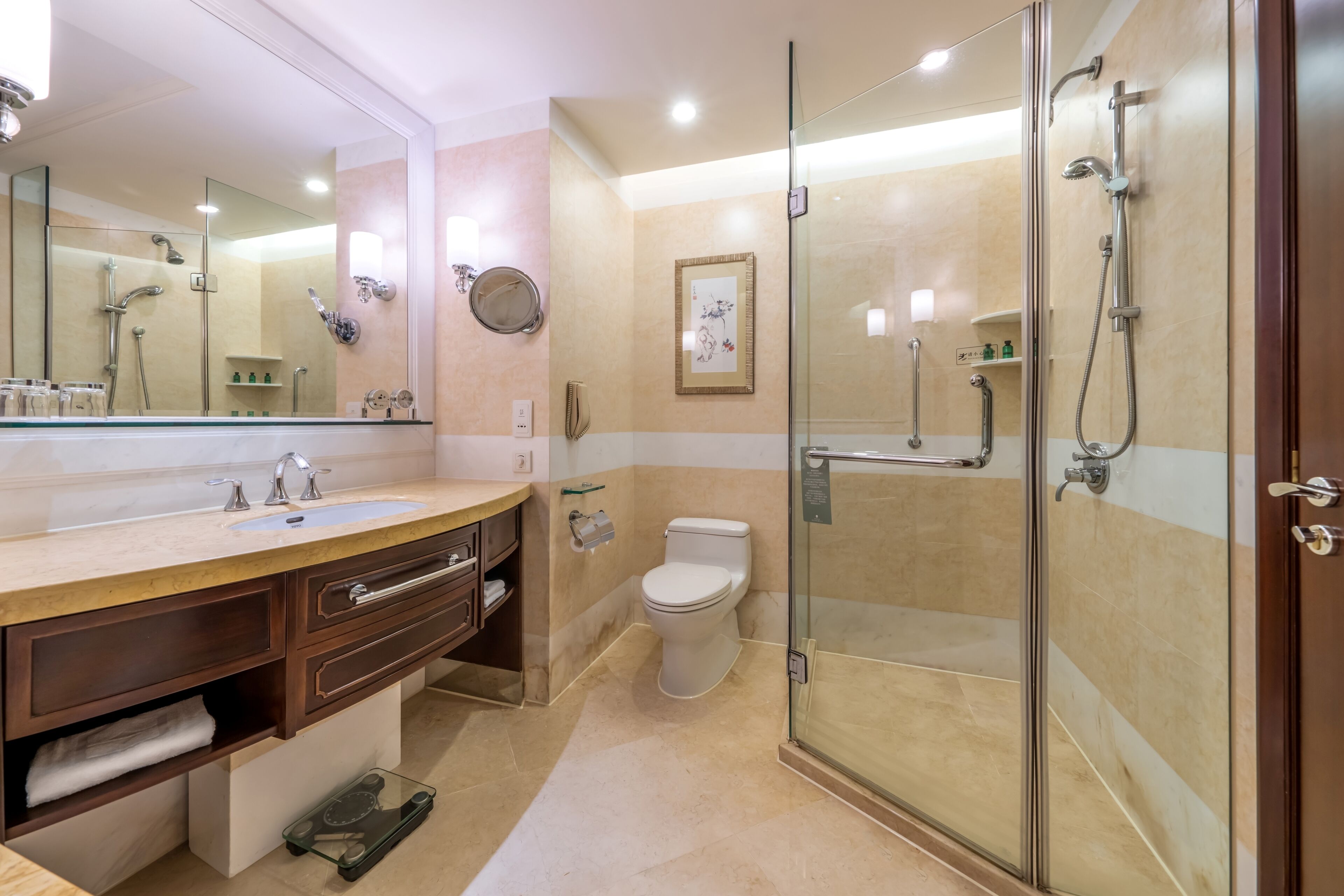 Une salle de bain moderne dotée d’une douche à parois de verre, d’un grand miroir et d’un meuble-lavabo avec un évier et un porte-serviettes.