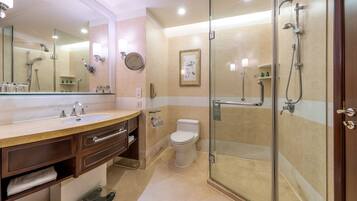 Une salle de bain moderne dotée d’une douche à parois de verre, d’un grand miroir et d’un meuble-lavabo avec un évier et un porte-serviettes.