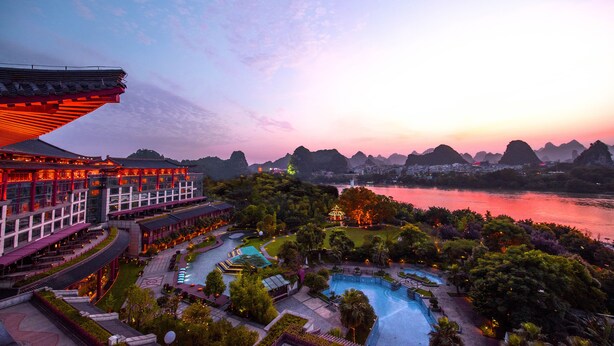 A resort with a swimming pool, landscaped gardens, and traditional architecture.