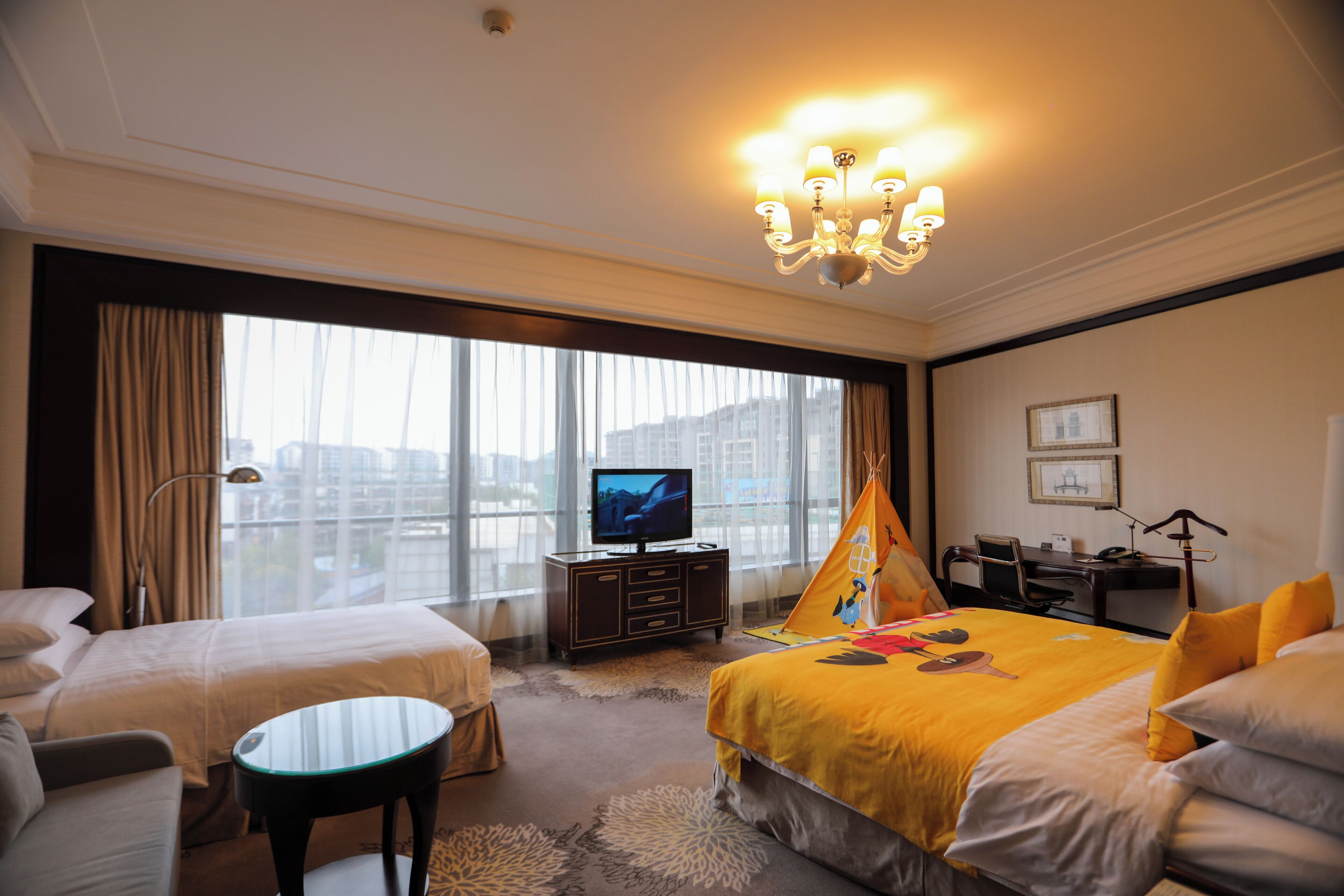 A hotel room with two beds, a television, a desk, and a chair.