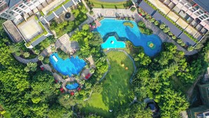 An aerial view of a resort with multiple swimming pools, lush greenery, and a well-maintained landscape.