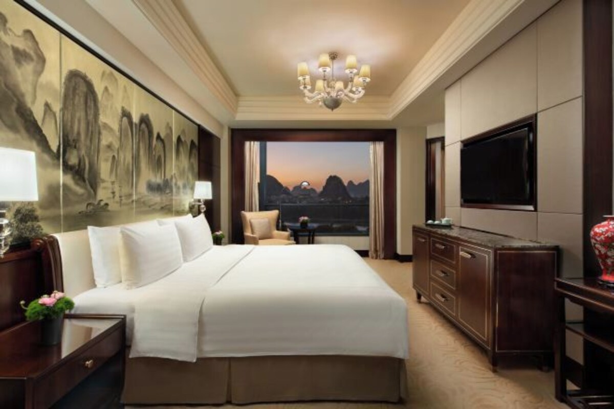 Habitación de hotel con una cama grande, televisión, escritorio y un cuadro en la pared.