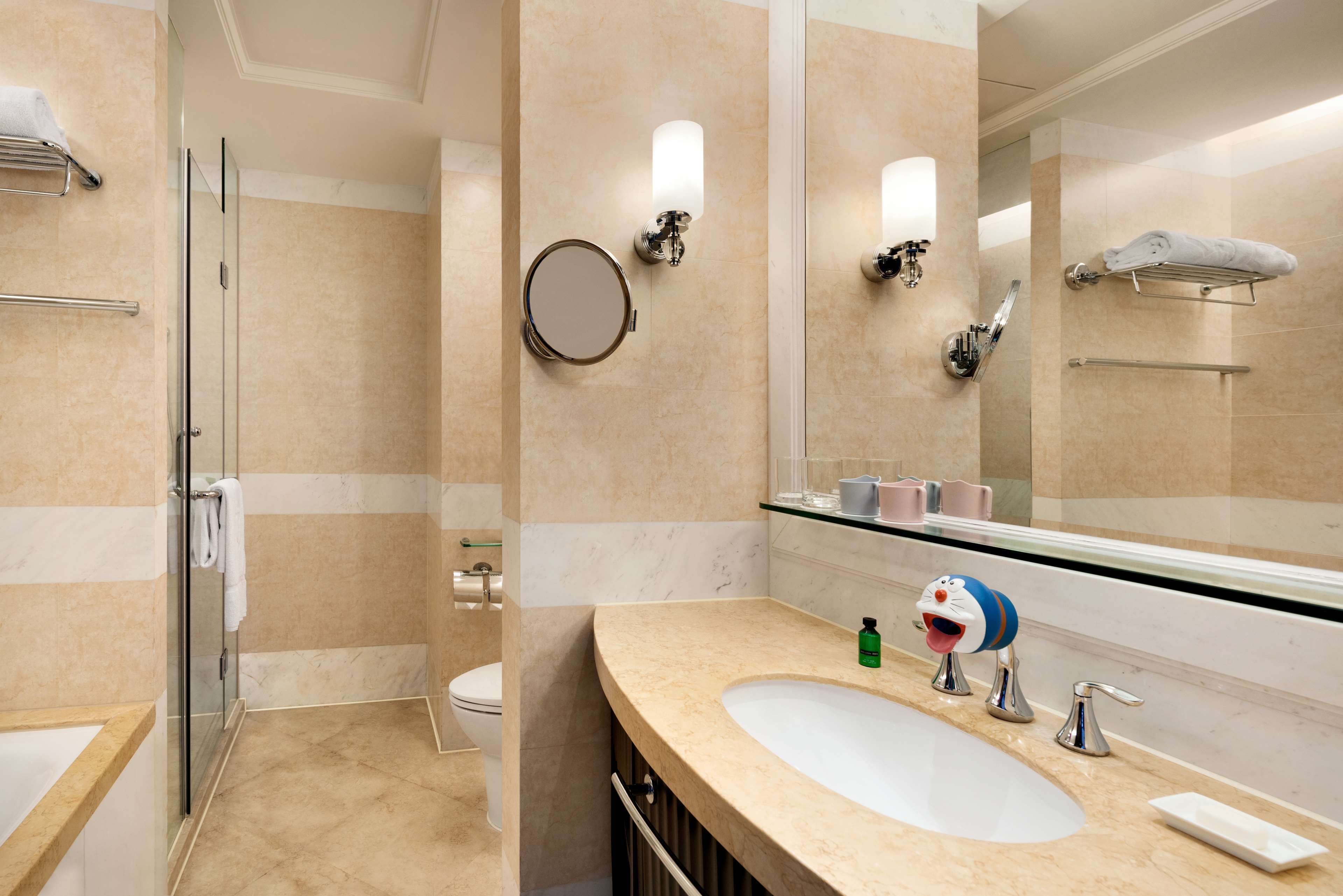 A modern bathroom with a glass shower enclosure, a large mirror, a sink with a vanity, and a towel rack.