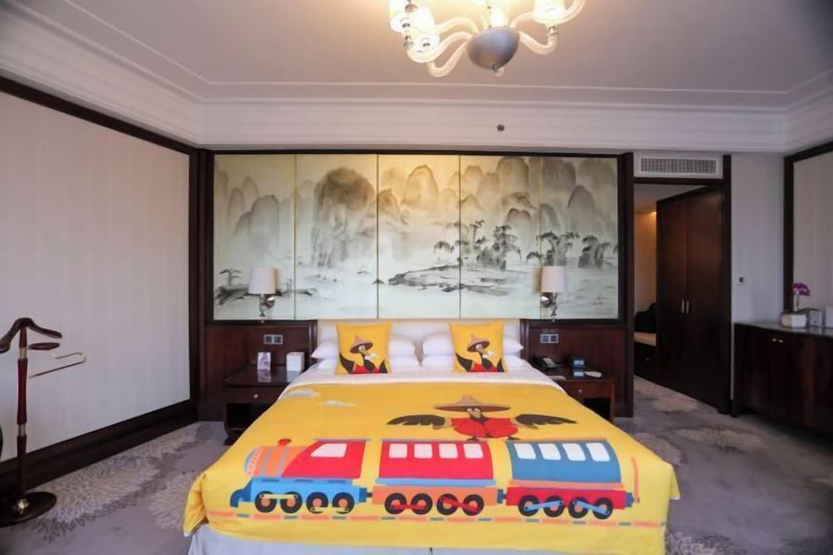 Una habitación de hotel con una cama grande, un cuadro tradicional en la pared y un candelabro moderno.