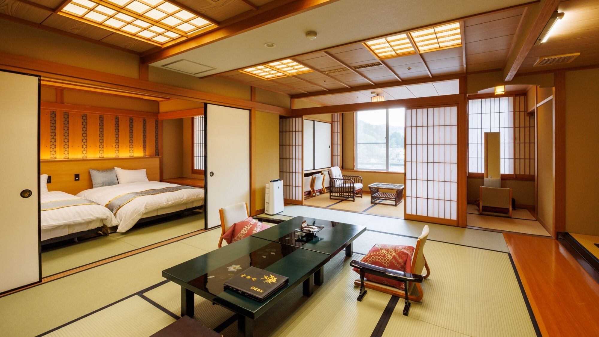 A traditional Japanese-style room with tatami flooring, a low table with a laptop, and a bed with a wooden headboard.