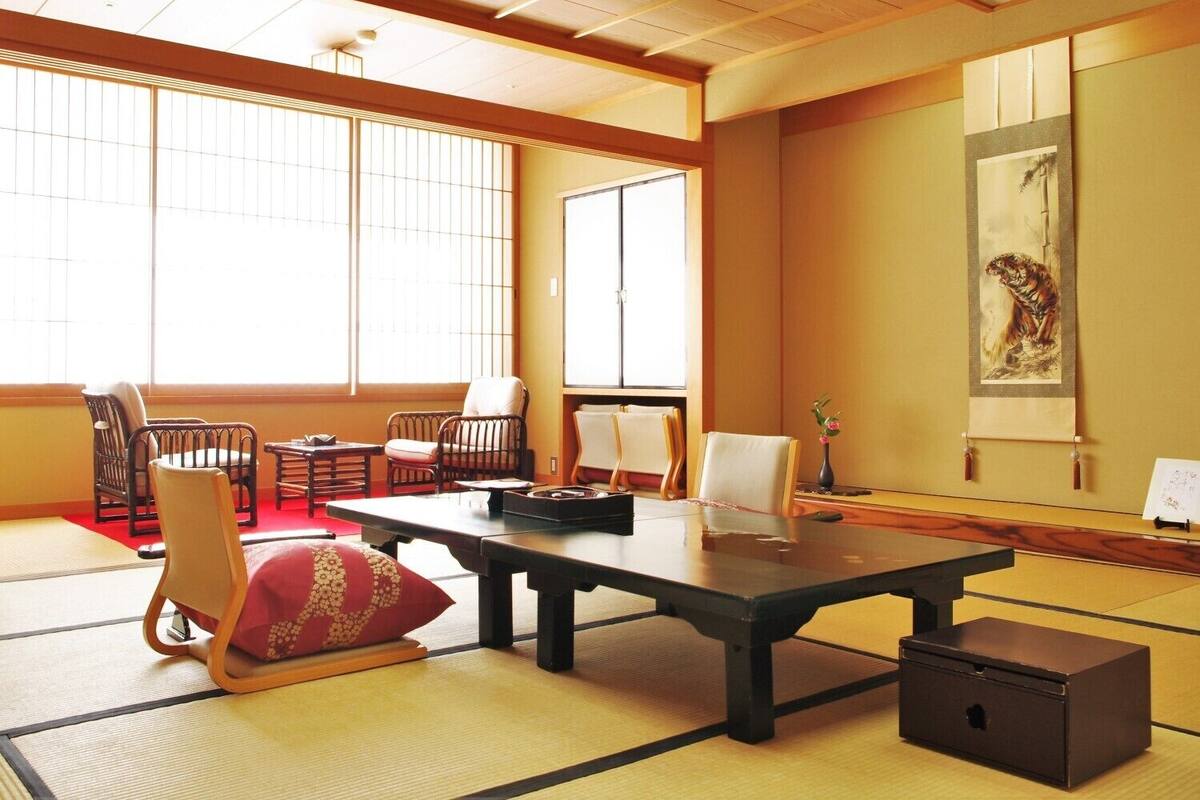 Ein traditioneller japanischer Raum mit Tatami-Boden, niedrigen Tischen und Sesseln.