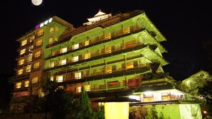 Un hotel de varios pisos con balcones, ventanas iluminadas y elementos arquitectónicos tradicionales.