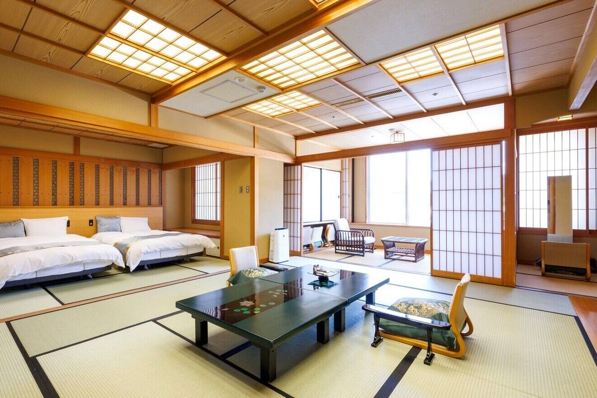 Ein traditioneller japanischer Raum mit Tatami-Böden, einem niedrigen Tisch und einem Bett mit hölzernem Kopfteil.