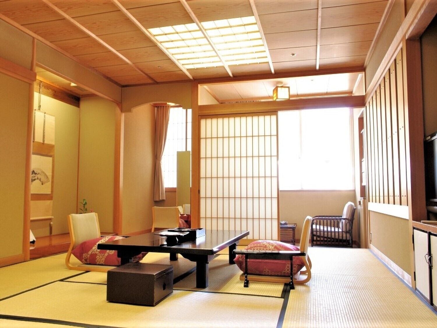 A traditional Japanese room with tatami flooring, a low table, a cushioned bench, and sliding doors.