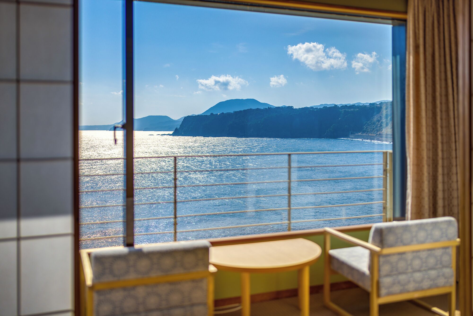 A balcony with a view of the sea and distant mountains.