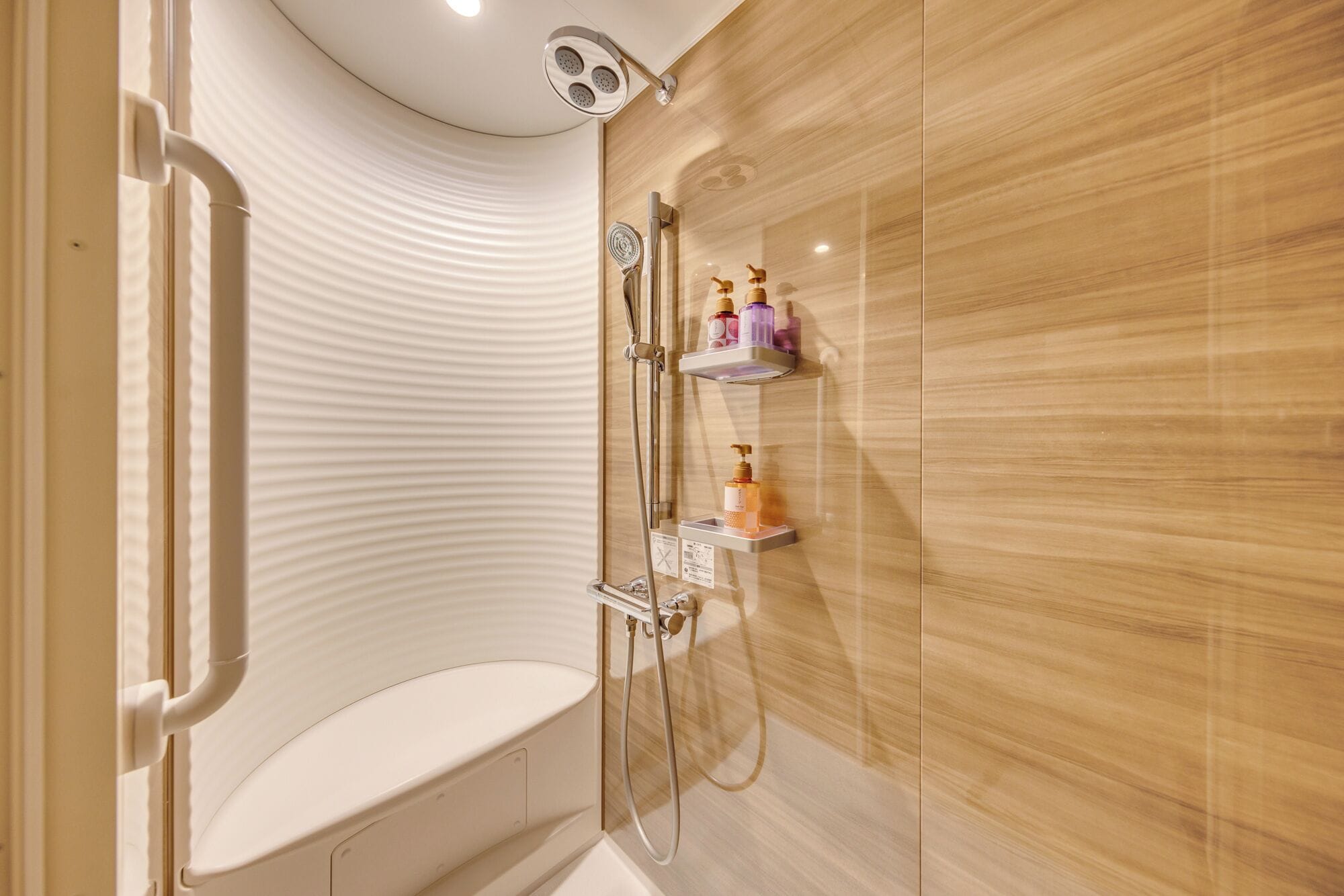 A modern bathroom with a shower, toilet, and wall-mounted shelves with toiletries.