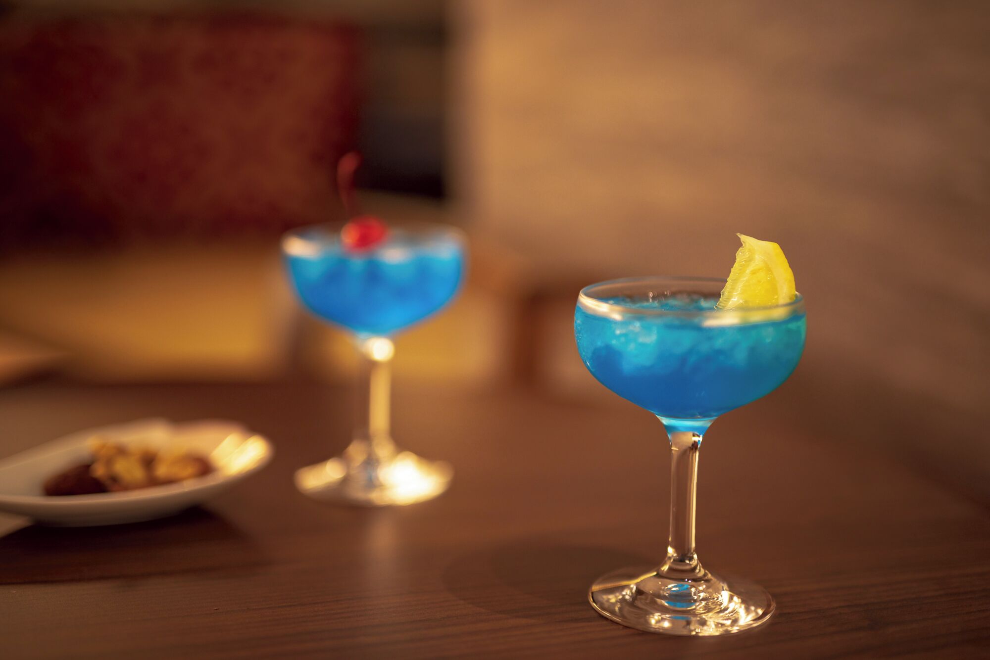 To cocktails i martini-glas på et træbord.