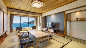 A room with a large table, chairs, a television, and a view of the sea. - Inatori-Ginsuiso (Higashiizu)