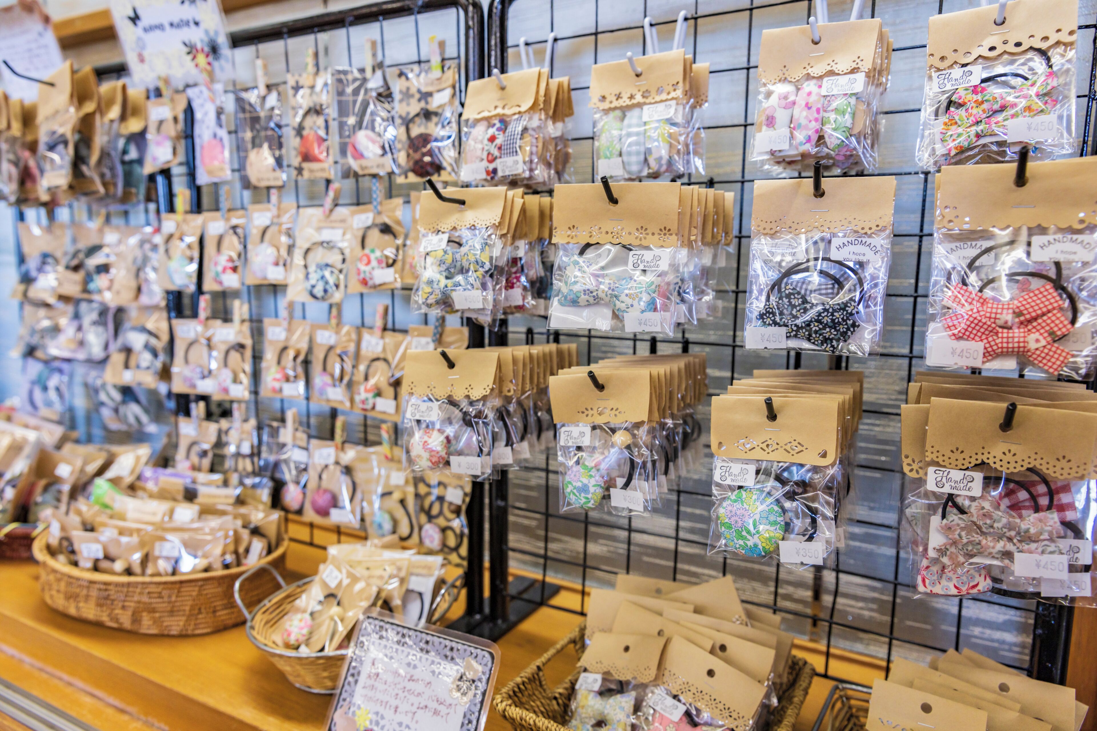 Exhibición de artículos artesanales con etiquetas de precio, incluyendo bolsos y accesorios, en un entorno de tienda.