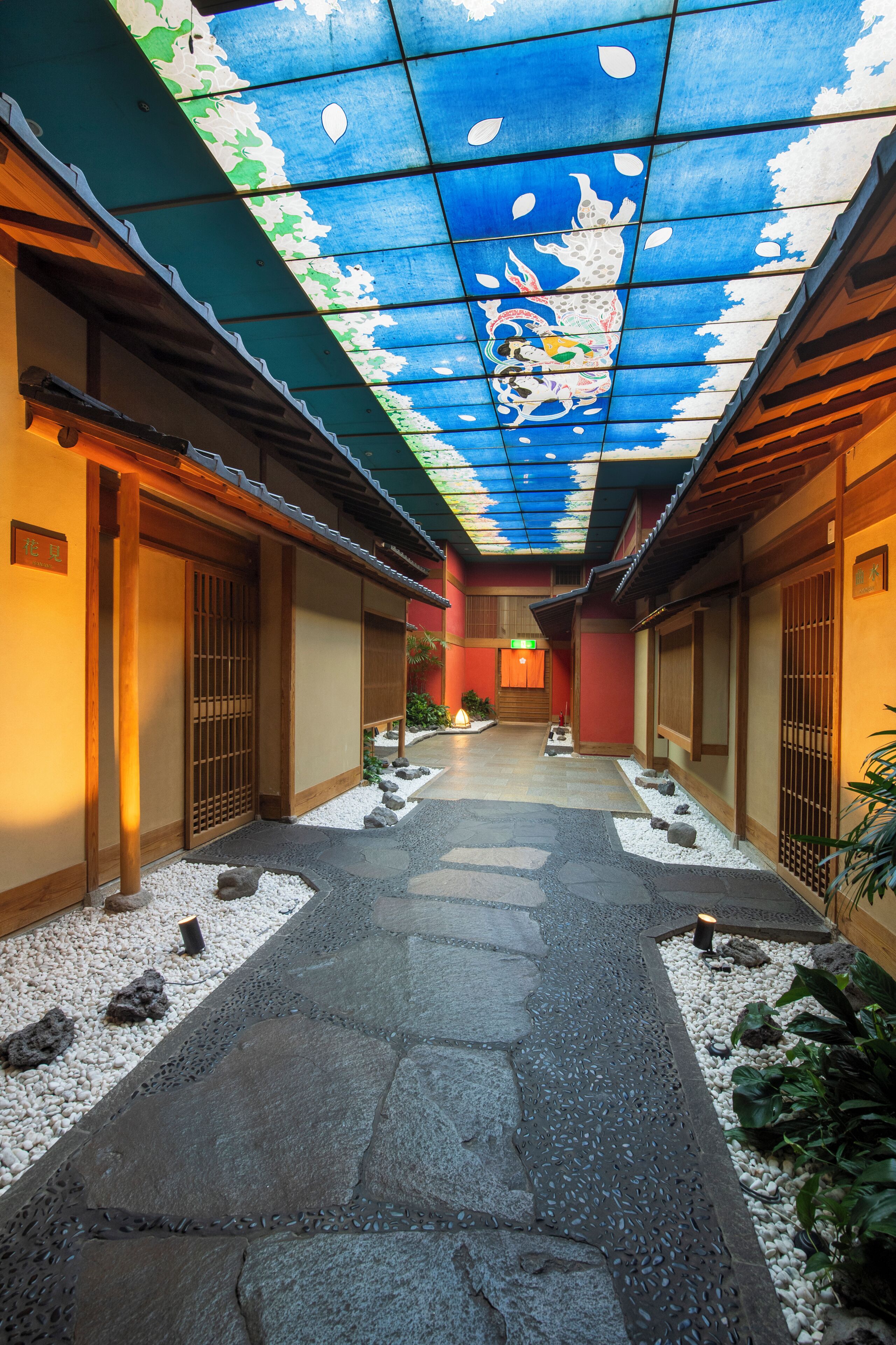 En traditionel japansk gang med tatamimåtter, trædøre og et loft med et farverigt mural.