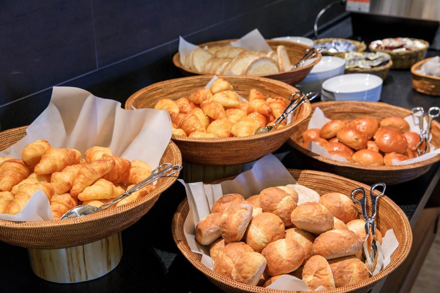 Un buffet proposant une variété de produits de boulangerie, notamment des croissants, des petits pains et des pâtisseries.