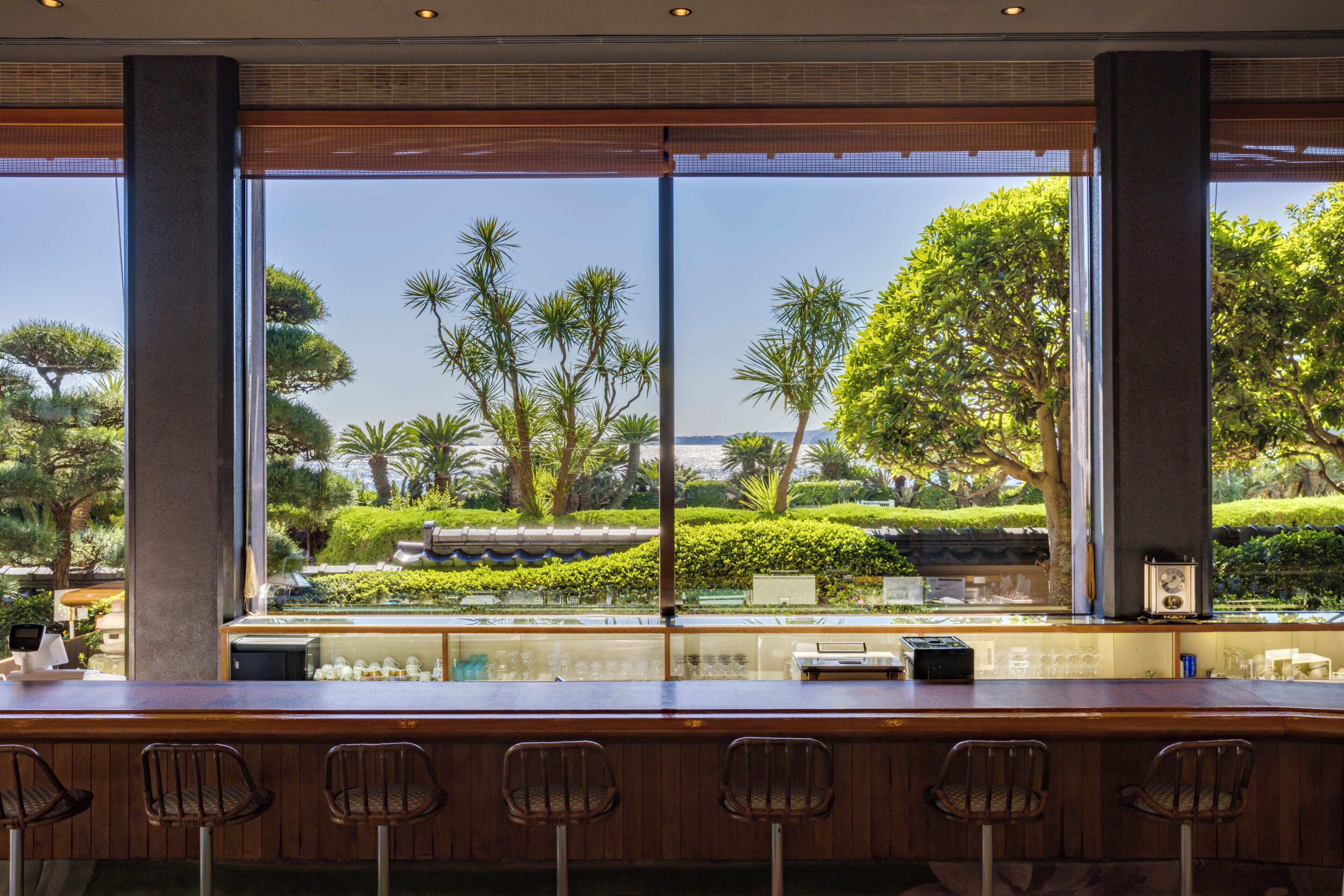 A bar area with a view of a landscaped garden through large windows.