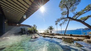 A clear pool with rocks, a wooden deck, and a view of the sea. - Inatori-Ginsuiso (Higashiizu)