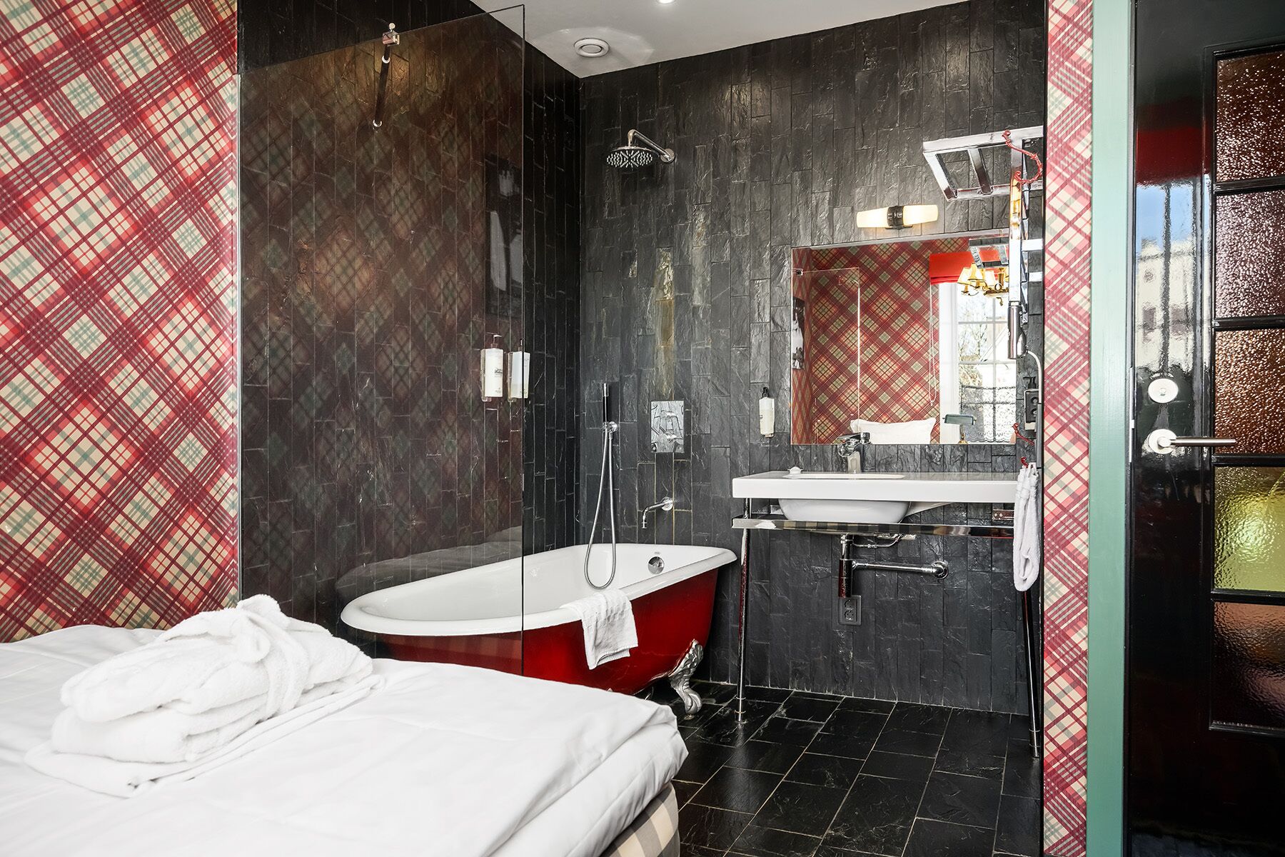 Un bagno moderno con una vasca da bagno rossa, un lavandino bianco e un grande specchio.