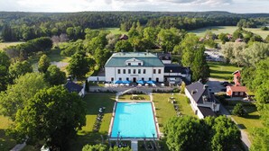 A large building with a swimming pool, surrounded by trees and a green landscape. - Häringe Slott (Vasterhaninge)