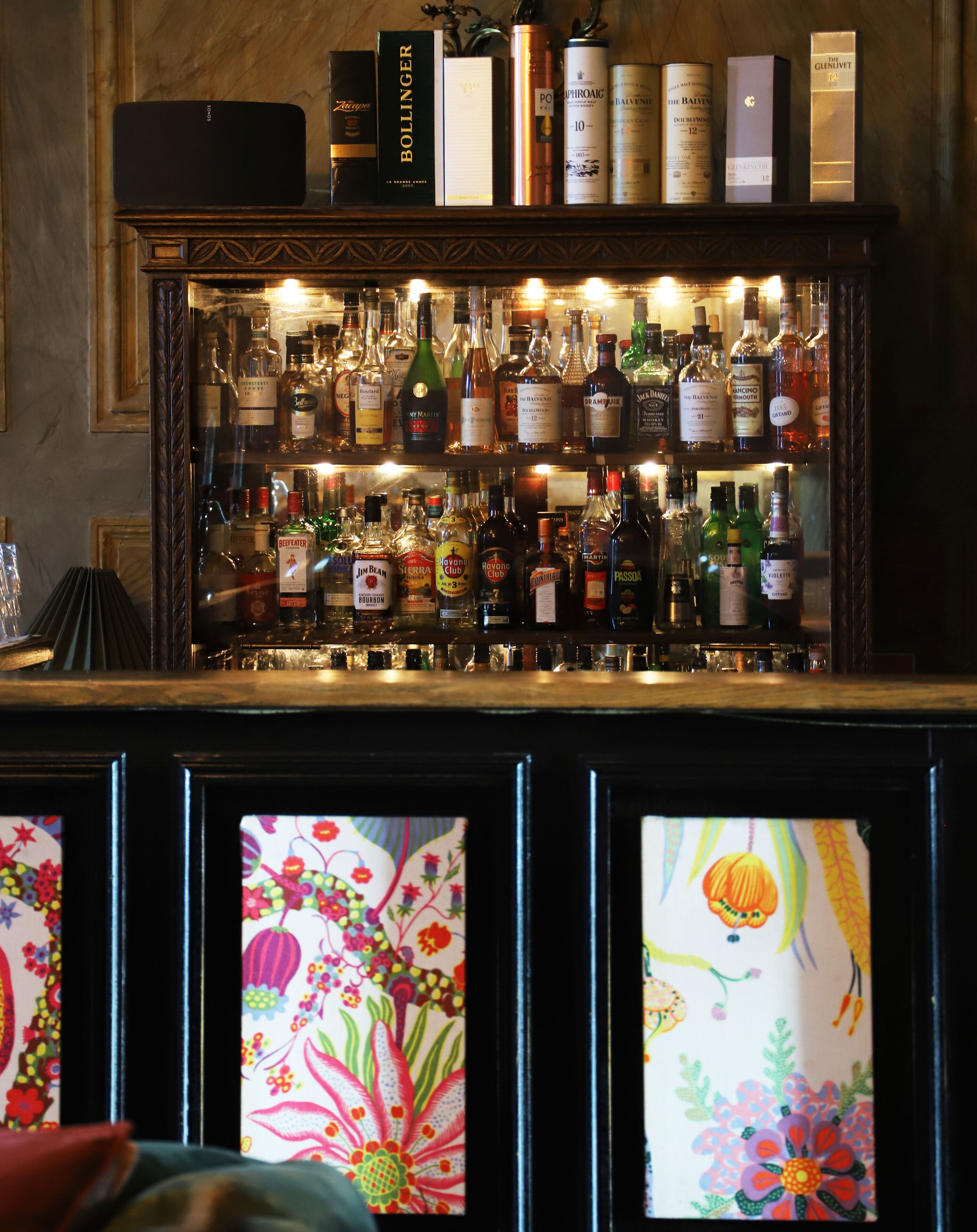 Zona de bar con estantes llenos de diferentes botellas de licores.