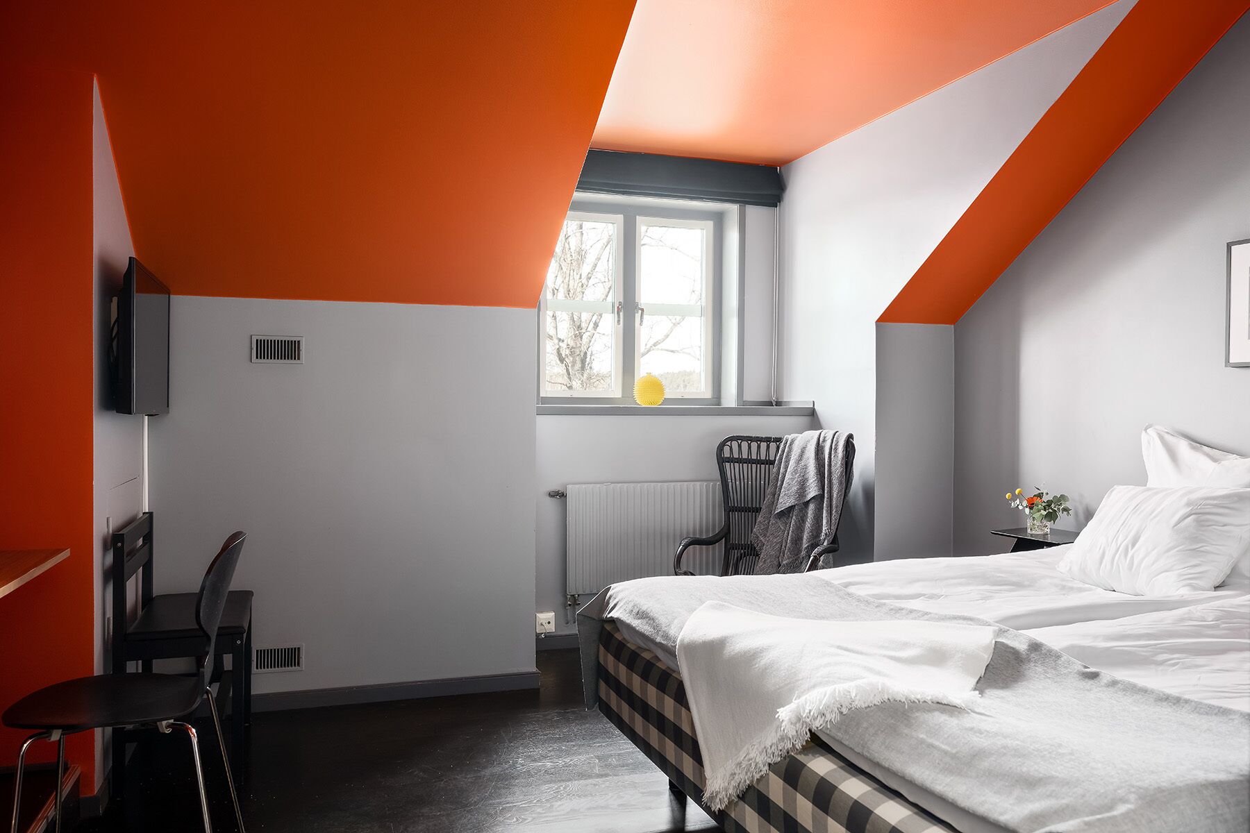 Un dormitorio con cama, una silla, un radiador y una ventana.