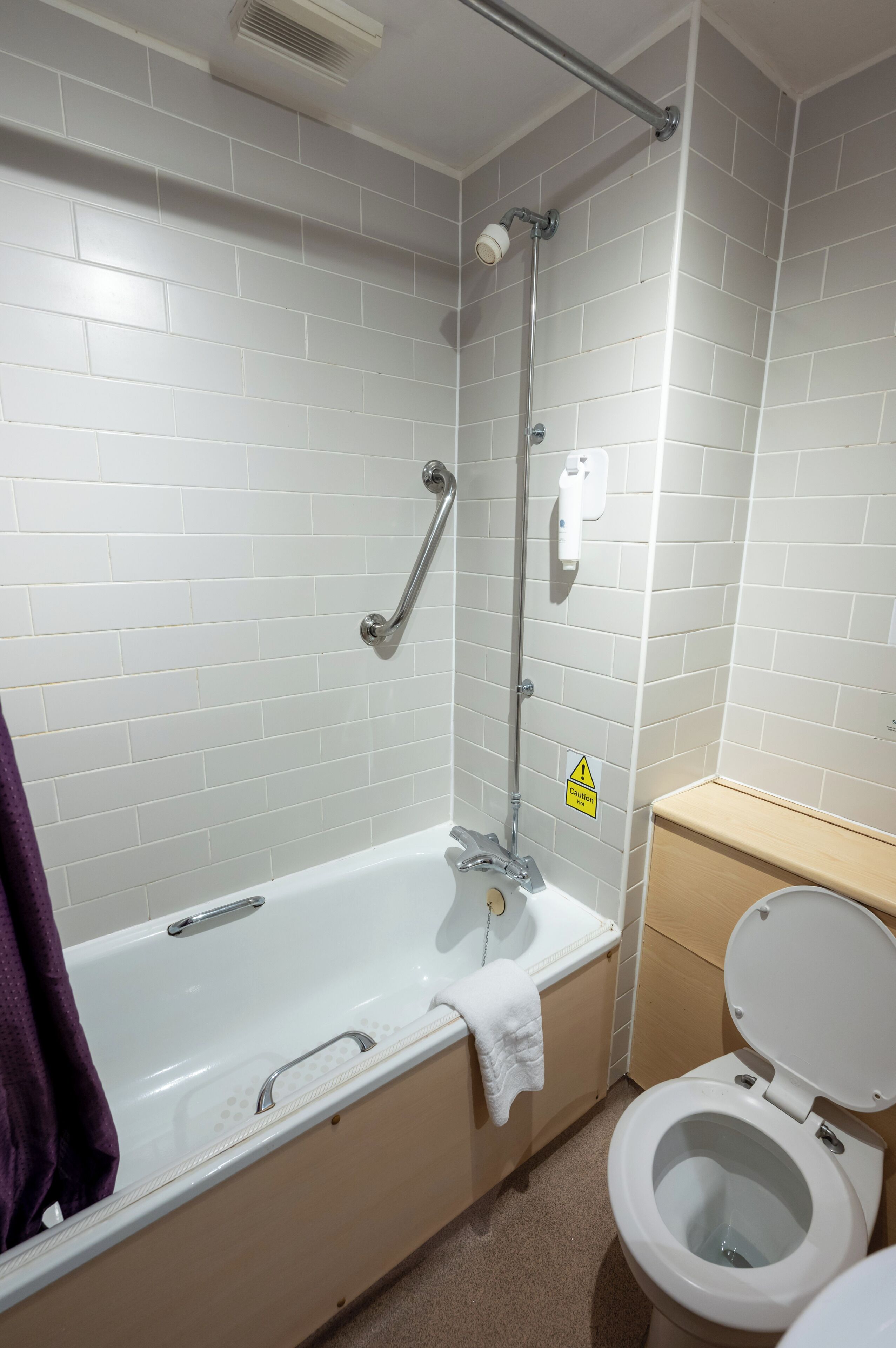 A bathroom with a bathtub, toilet, and a shower area.