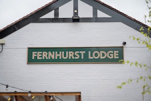 Un cartel para Fernhurst Lodge en un edificio de ladrillo blanco con techo negro.