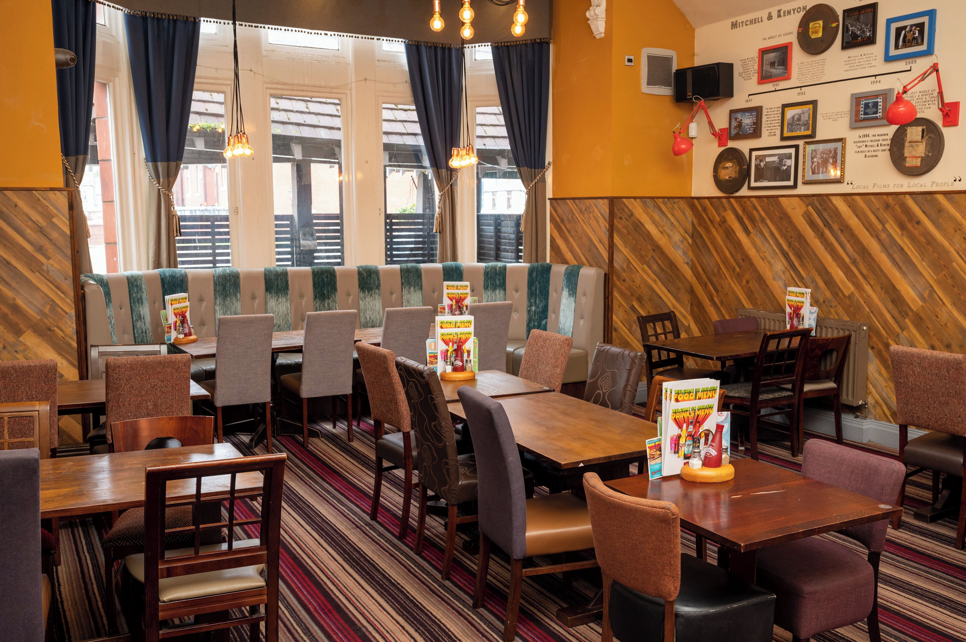 A restaurant with booths and tables, wooden walls, and a wall with framed photos and text.