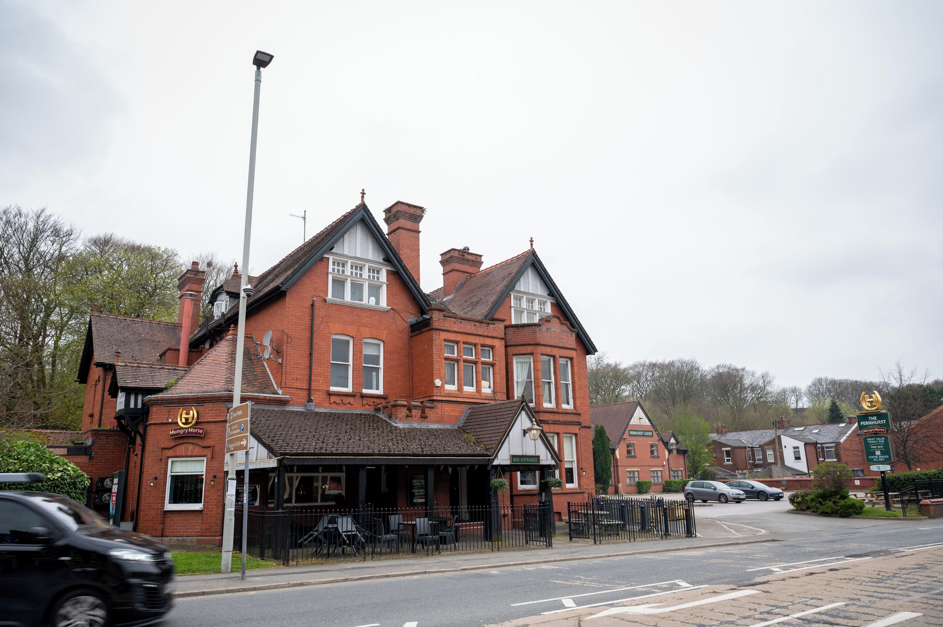 A traditional red brick building with a pub sign, a signboard for 'The Manor House', and a 'P' parking sign.