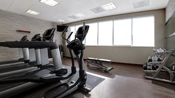 A gym with treadmills, elliptical machines, and weight benches.