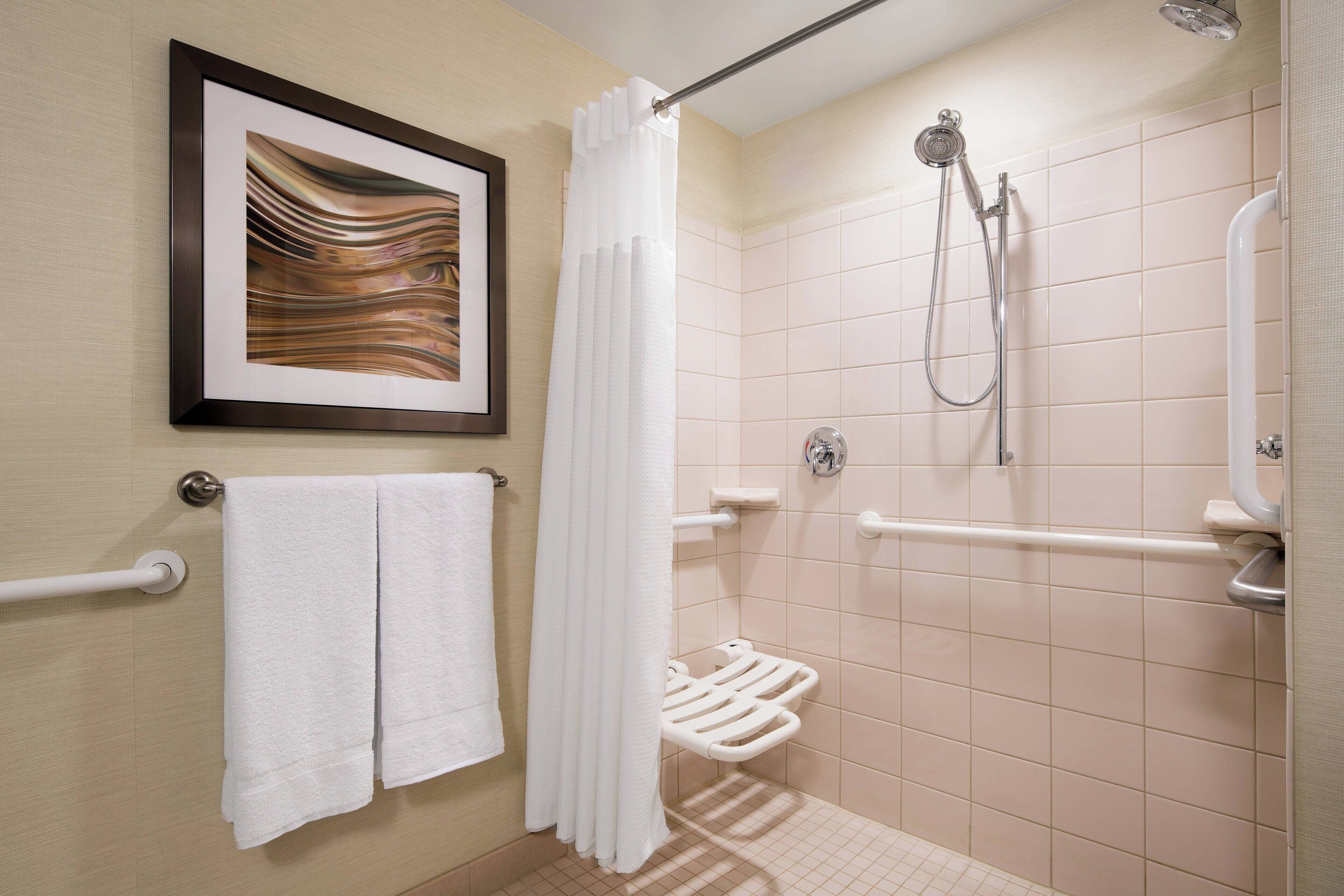 A bathroom with a shower, a framed artwork, and a towel rack.