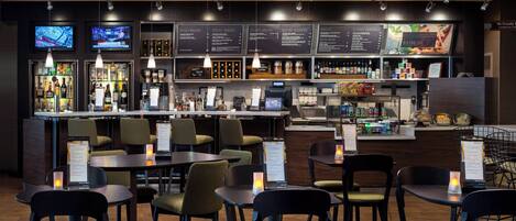 A restaurant with a bar area, menu boards, and seating arrangements.
