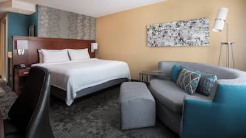 Une chambre d’hôtel avec un lit, un canapé, un bureau et une lampe.