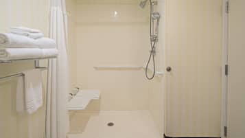 A small, clean bathroom with a shower, a toilet, and a sink. There are towels on a rack and a shower curtain.