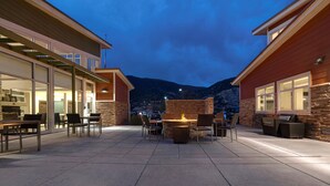 Un patio con mobiliario exterior, una chimenea y montañas al fondo.