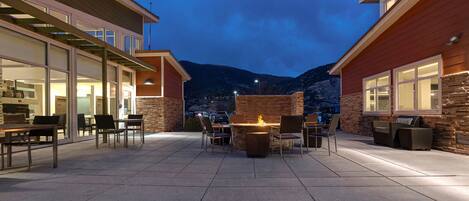 Un patio con mobiliario exterior, una chimenea y montañas al fondo.
